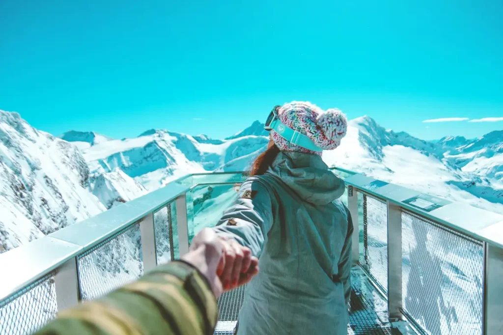 How to Propose to Your Loved One: Top Marriage Proposal Ideas | Take A Vow Stories a man holding a girl hand looking at snow mountain
