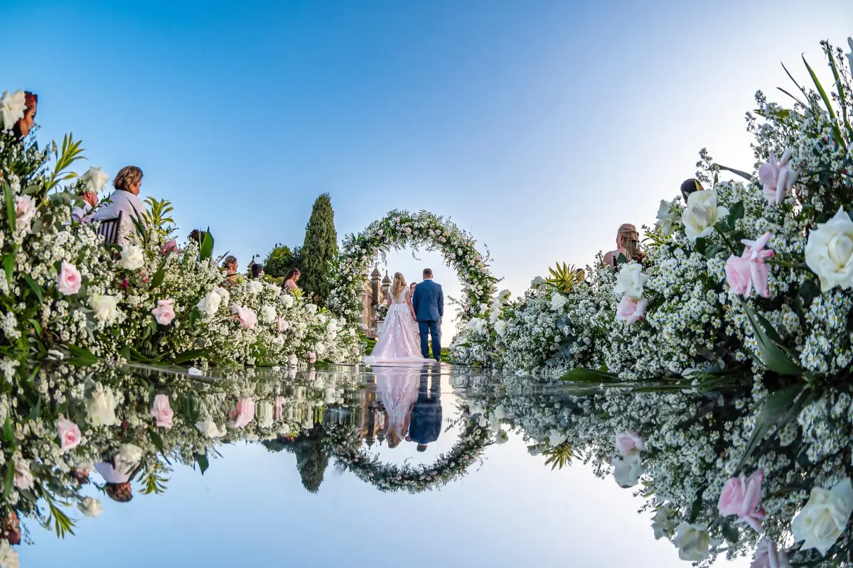 a man and woman in a wedding dress under a flower arch